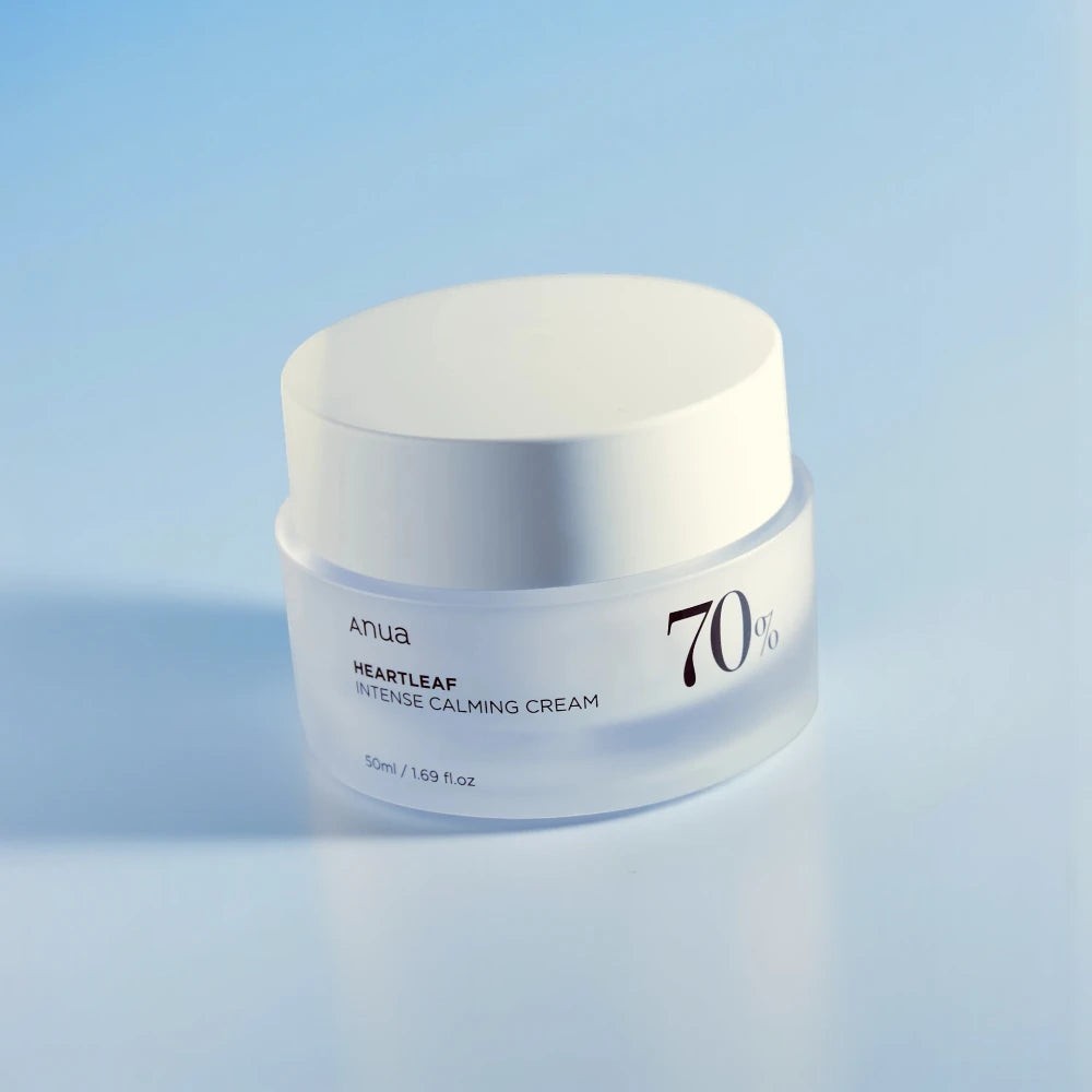 Skin TOGO Anua Heartleaf 70 Intense Calming Cream in a frosted glass jar with a white lid on a blue background.
