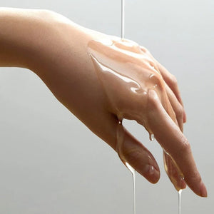 Skin TOGO Anua Heartleaf Pore Control Cleansing Oil texture shown as a clear liquid dripping over a person's hand.