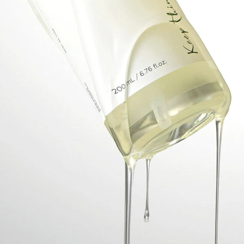 Skin TOGO Anua Heartleaf Pore Control Cleansing Oil dripping from a clear bottle against a white background