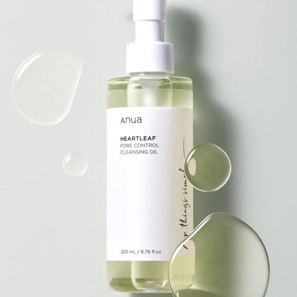 Skin TOGO Anua Heartleaf Pore Control Cleansing Oil in a clear pump bottle with droplets of oil on a soft green background