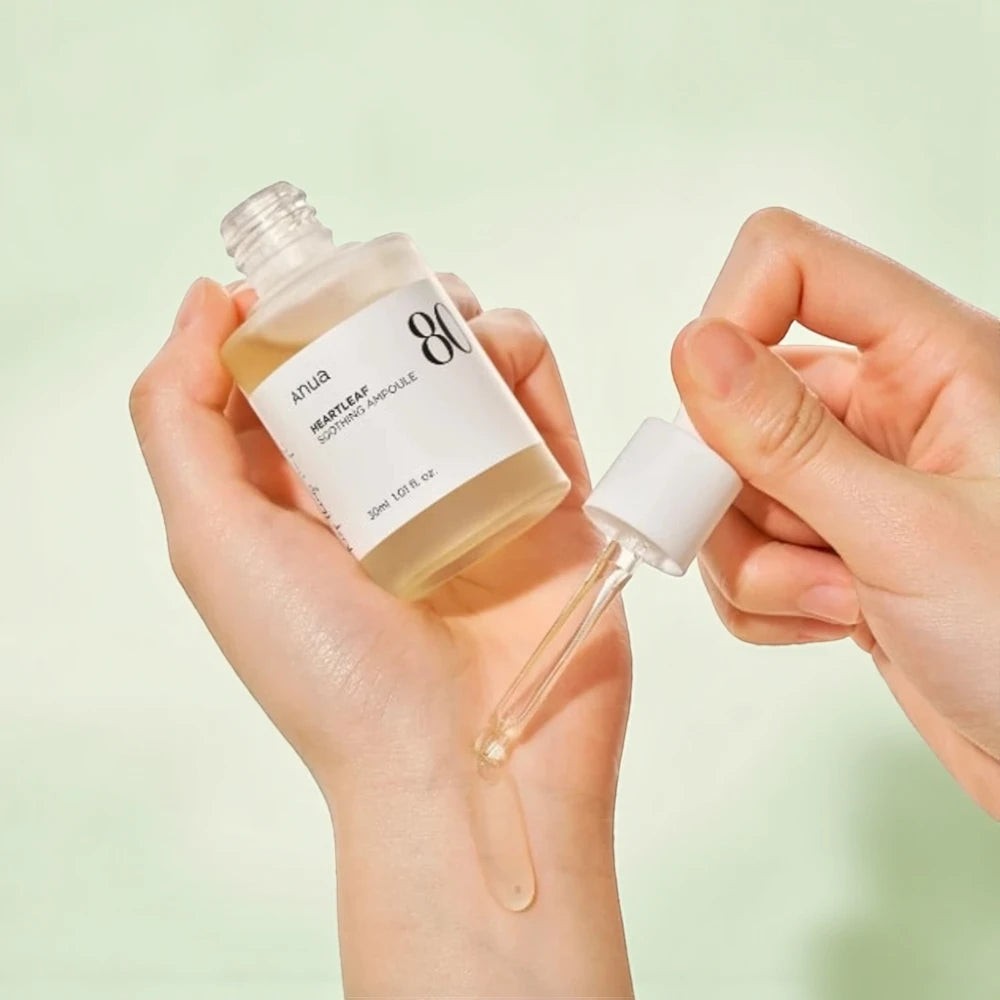 Skin TOGO Anua Heartleaf 80% Soothing Ampoule serum being applied with a dropper onto a hand for skincare.
