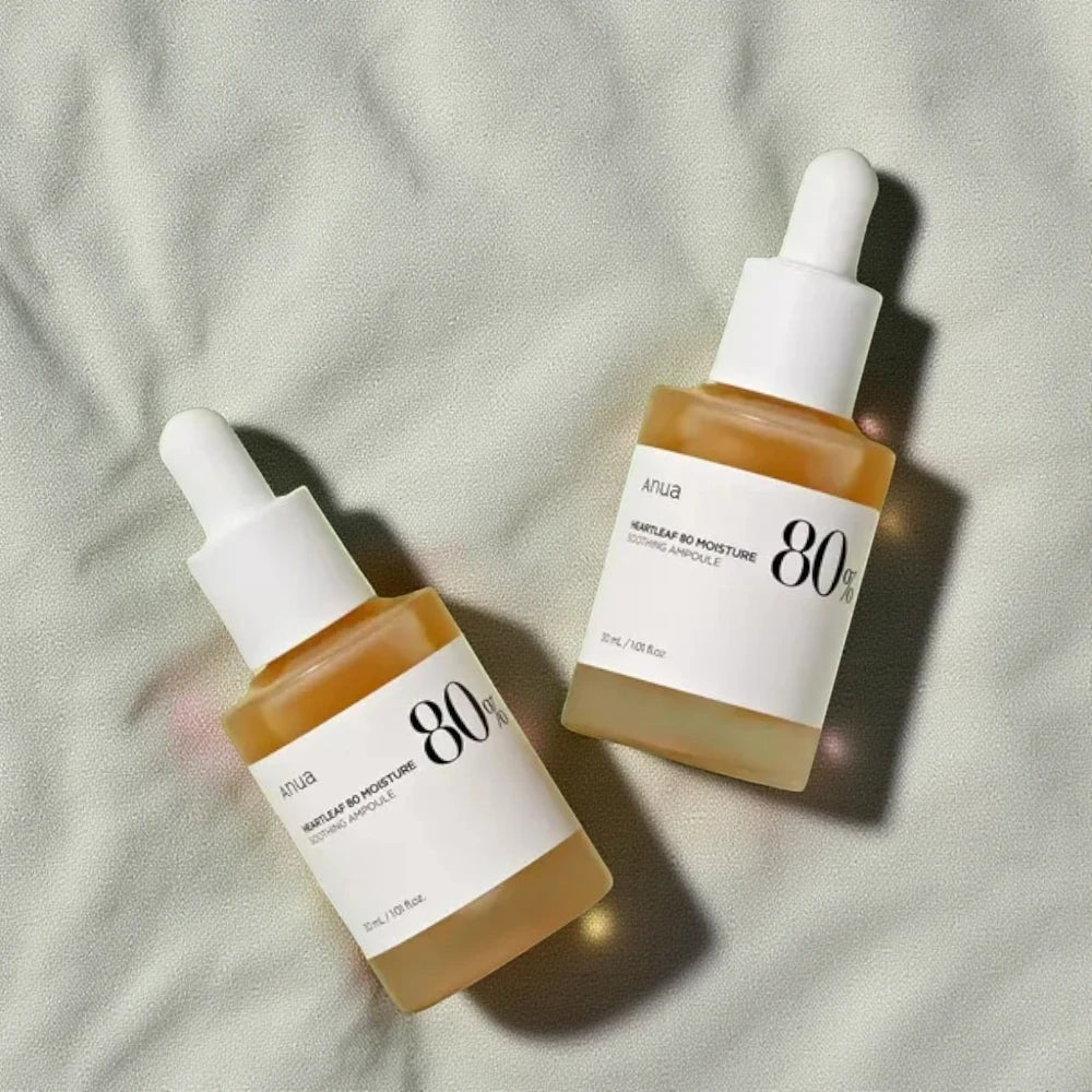 Skin TOGO Anua Heartleaf 80% Soothing Ampoule bottles with dropper caps on a soft textured fabric background.