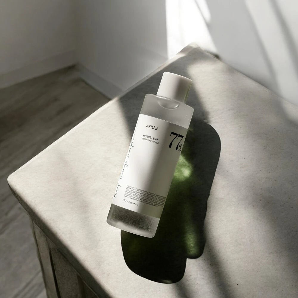 Skin TOGO Anua Heartleaf 77 Soothing Toner in a clear 250ml bottle on a stone surface with natural sunlight shadows.