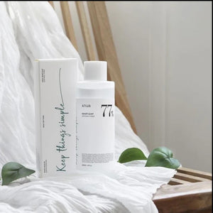Skin TOGO Anua Heartleaf 77 Soothing Toner bottle and box on a wooden chair with white fabric and green leaves
