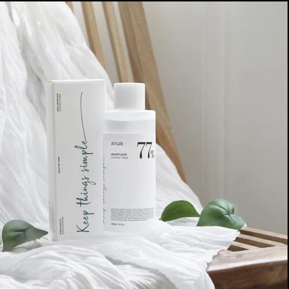 Skin TOGO Anua Heartleaf 77 Soothing Toner bottle and box on a wooden chair with white fabric and green leaves