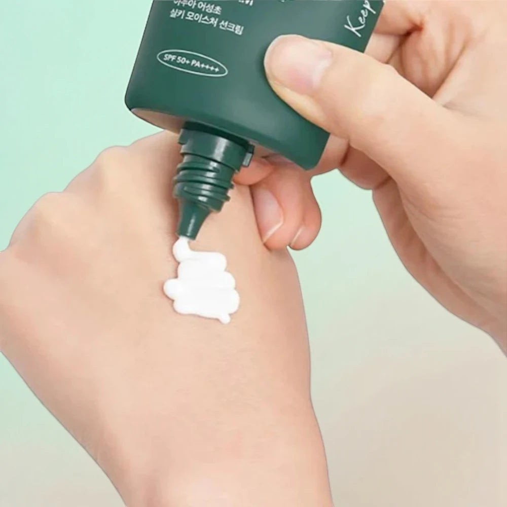 Skin TOGO Anua Heartleaf Silky Moisture Sun Cream being squeezed onto a hand, showing its white creamy texture.