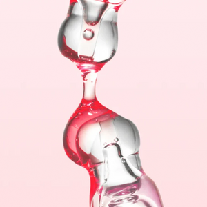 Skin TOGO Anua Niacinamide 10% and TXA 4% serum texture showing clear and pink liquid droplets against a soft background