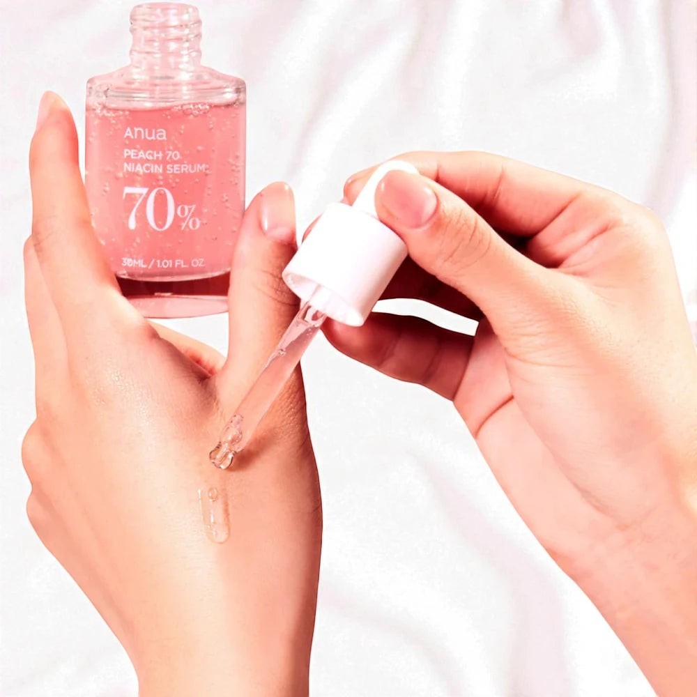 Skin TOGO Anua Peach 70% Niacin Serum being applied with a dropper to a hand, showing the clear, lightweight texture.