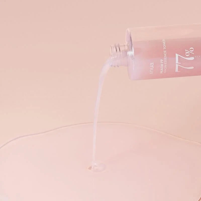 Skin TOGO Anua Peach 77 Niacin Conditioning Milk Toner pouring its creamy, milky texture onto a soft peach surface.