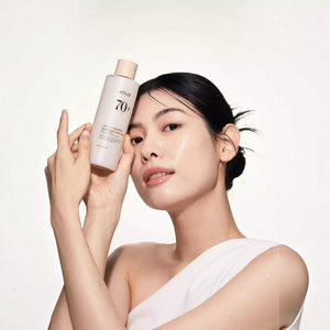 Skin TOGO model holding Anua Rice 70 Glow Milky Toner, showcasing radiant skin and the 250ml bottle packaging.