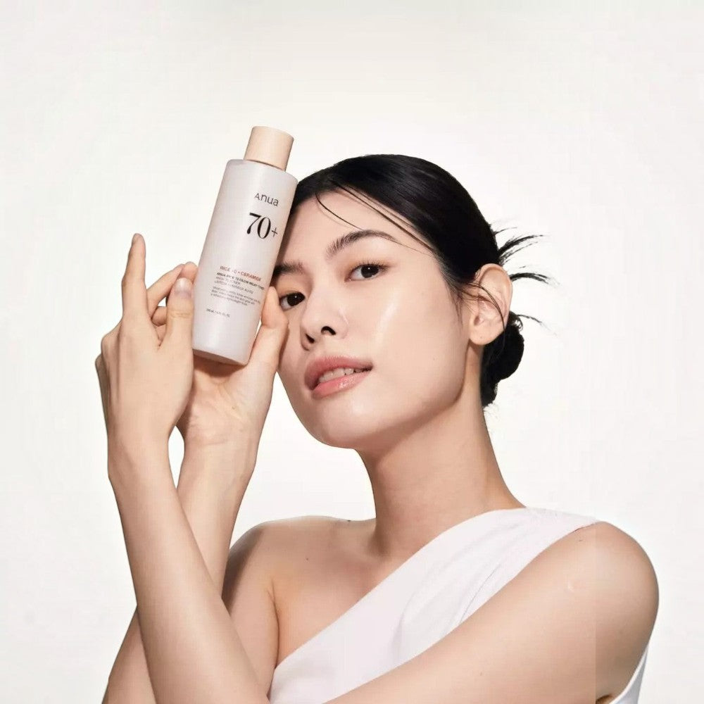 Skin TOGO model holding Anua Rice 70 Glow Milky Toner, showcasing radiant skin and the 250ml bottle packaging.