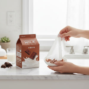 Skin TOGO A'PIEU Milk One Pack Chocolate sheet mask packaging with a hand holding a mask over a bowl of chocolate.