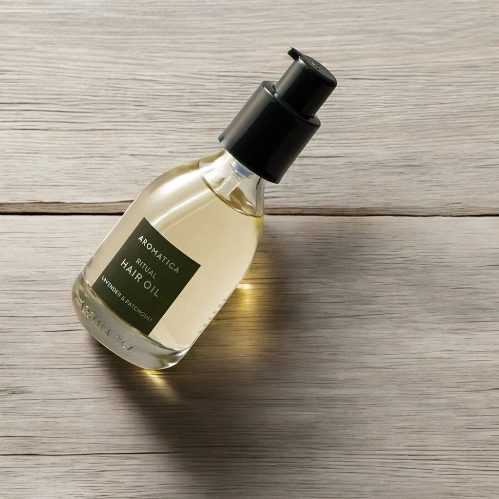 Skin TOGO Aromatica Ritual Hair Oil with lavender and patchouli in a 50ml glass pump bottle on a wooden surface.