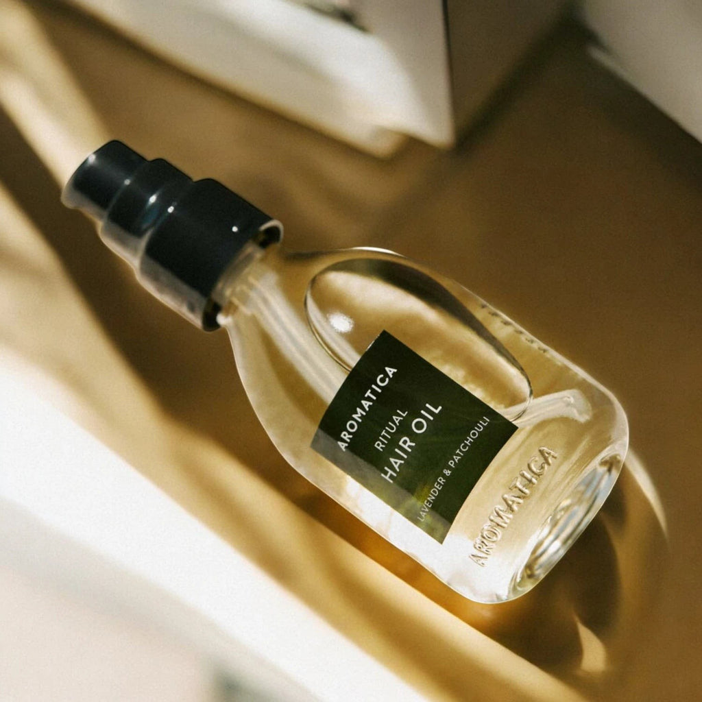 Skin TOGO Aromatica Ritual Hair Oil with lavender and patchouli in a 50ml glass pump bottle on a sunlit surface.