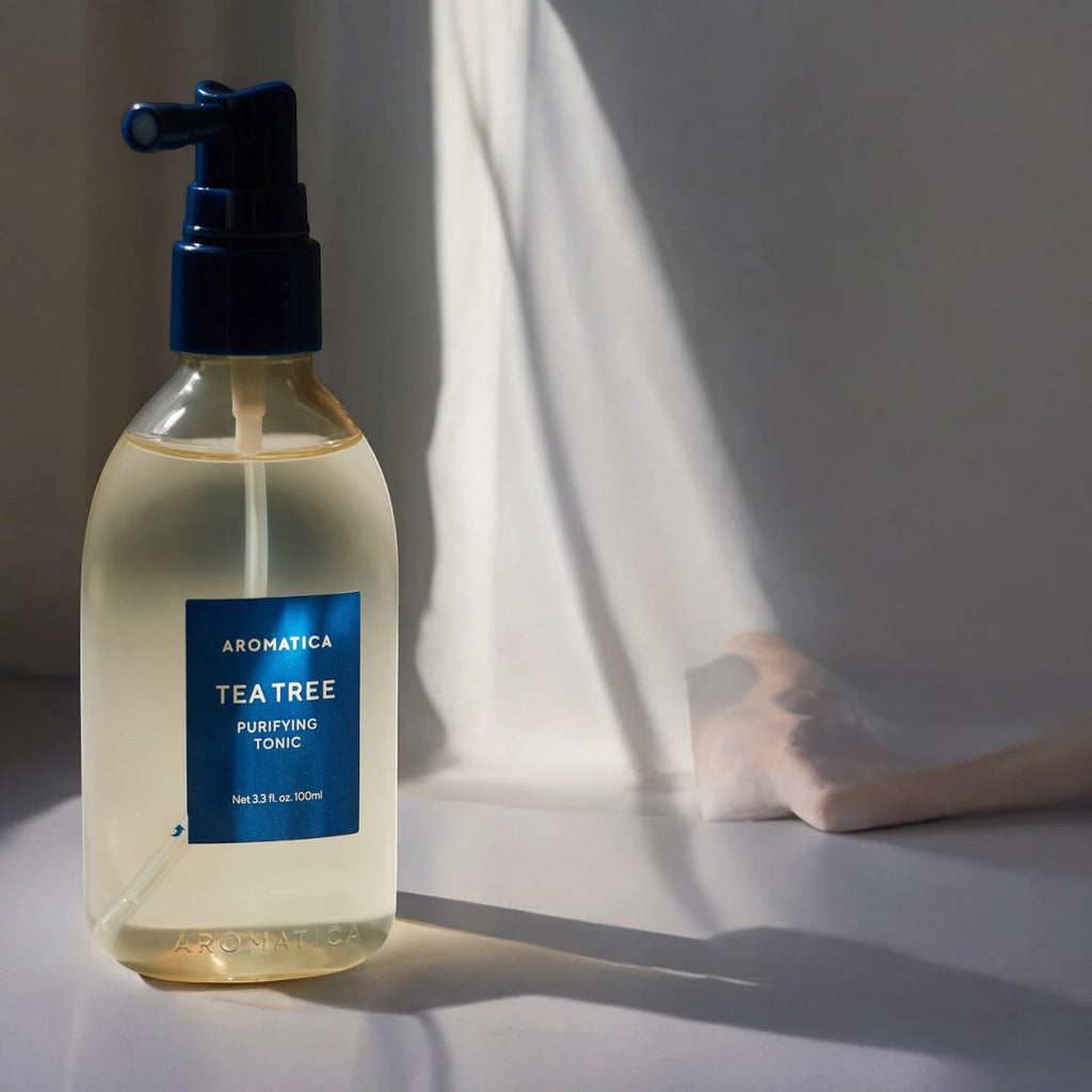 Skin TOGO Aromatica Tea Tree Purifying Tonic in a clear 100ml spray bottle with a blue pump on a sunlit surface.