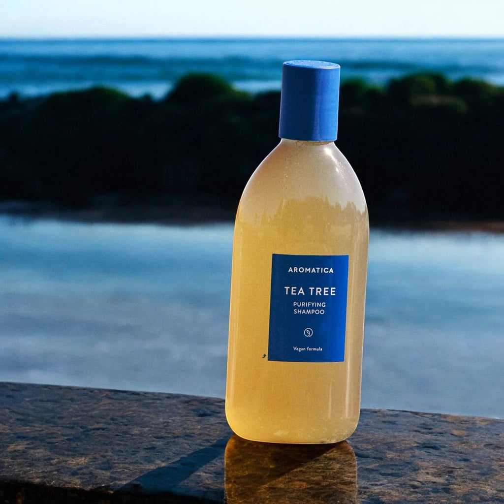 Skin TOGO Aromatica Tea Tree Purifying Shampoo in a clear bottle with a blue cap, set against a blurred ocean view.