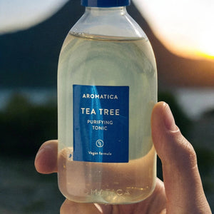 Skin TOGO Aromatica Tea Tree Purifying Tonic in a clear 100ml spray bottle held against a sunset background.