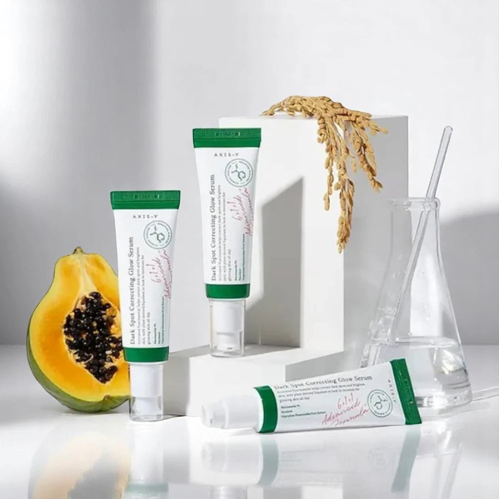 Skin TOGO Axis-Y Dark Spot Correcting Glow Serum tubes with papaya and rice stalks on a white minimalist background.