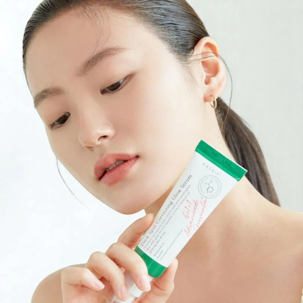 Skin TOGO model holding Axis-Y Dark Spot Correcting Glow Serum in a white and green tube for skin brightening