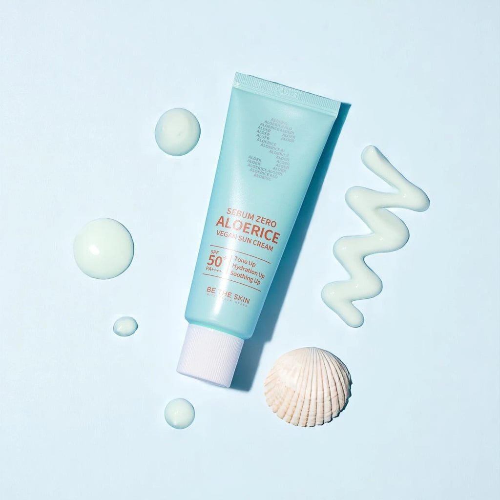 Skin TOGO Be The Skin Sebum Zero Aloerice SPF 50+ suncream tube with cream swatches and a seashell on blue background