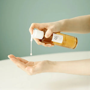 Skin TOGO Beauty of Joseon Ginseng Cleansing Oil being dispensed from a pump bottle into a hand for skincare routine