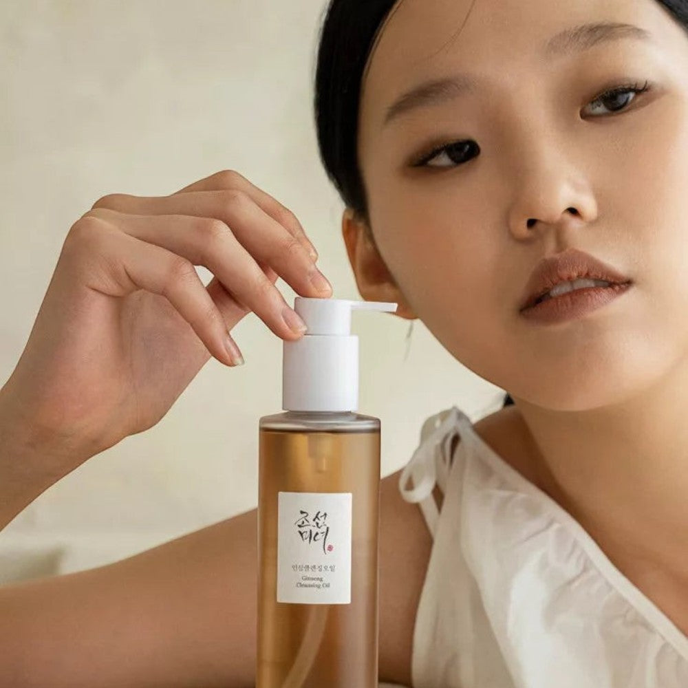 Skin TOGO model holding a bottle of Beauty of Joseon Ginseng Cleansing Oil for deep facial makeup removal