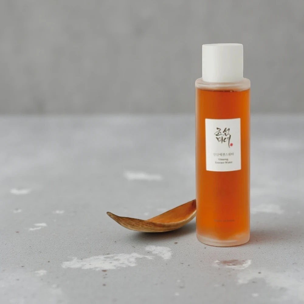 Skin TOGO Beauty of Joseon Ginseng Essence Water in a clear bottle with amber liquid and a wooden spoon on grey stone