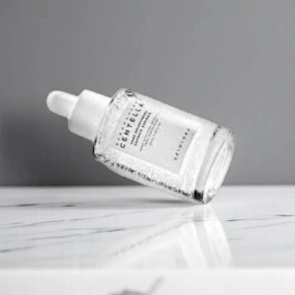 Skin TOGO Centella Tone Capsule Ampoule in a clear glass bottle with visible brightening capsules on a marble surface.