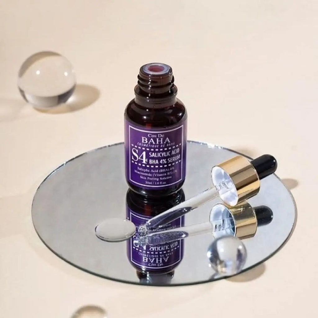 Skin TOGO Cos De BAHA S4 Salicylic Acid 4% BHA serum in a dark glass bottle with a dropper on a reflective mirror.