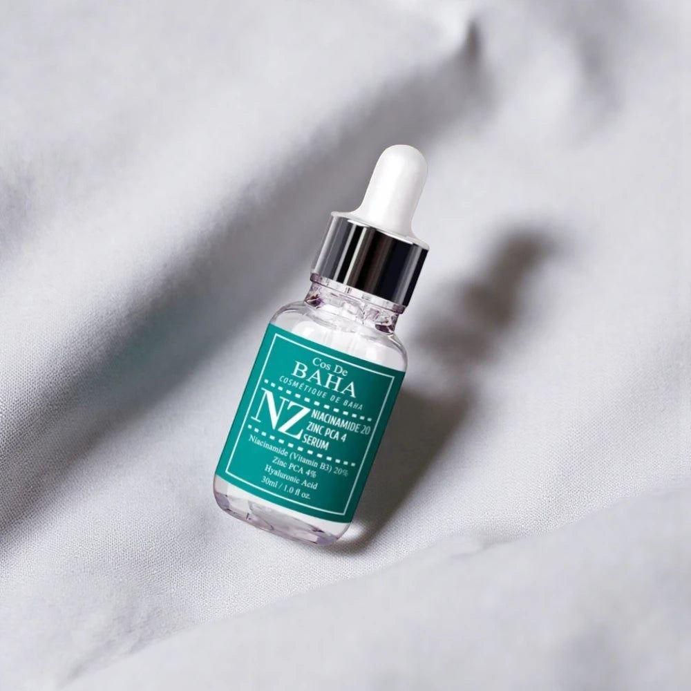 Skin TOGO Cos De BAHA NZ Niacinamide 20% and Zinc PCA 4% serum in a 30ml glass dropper bottle on grey fabric.