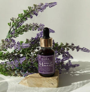 Skin TOGO Cos De BAHA S4 Salicylic Acid 4% BHA serum bottle with a dropper, displayed on a stone with lavender flowers.