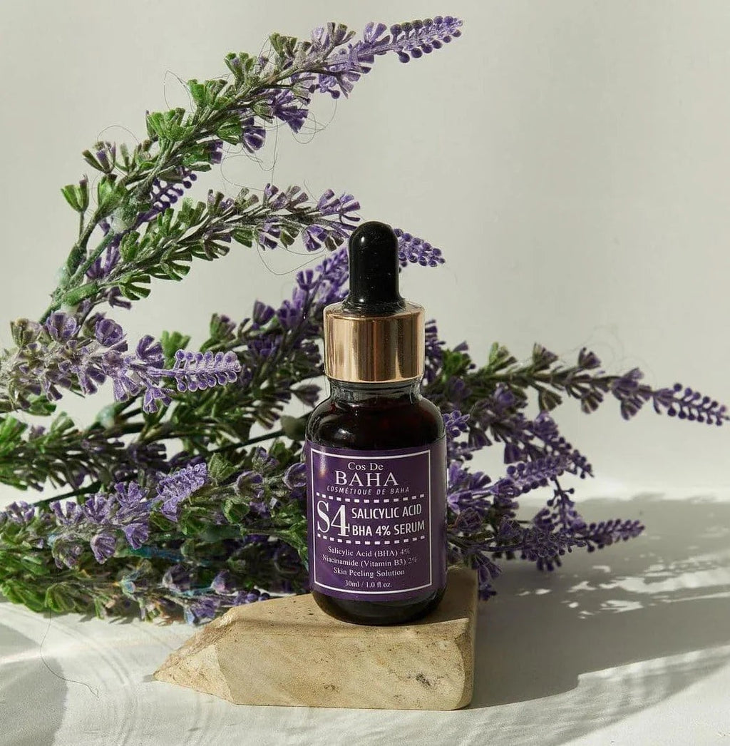 Skin TOGO Cos De BAHA S4 Salicylic Acid 4% BHA serum bottle with a dropper, displayed on a stone with lavender flowers.