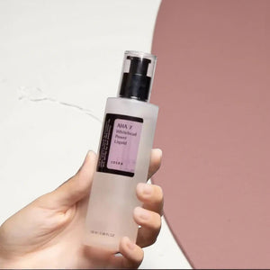 Skin TOGO Cosrx AHA 7 Whitehead Power Liquid chemical exfoliant in a clear 100ml pump bottle held in a hand.