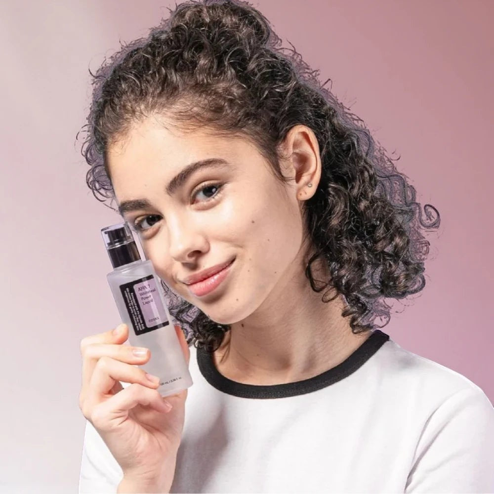 Skin TOGO model holding a bottle of Cosrx AHA 7 Whitehead Power Liquid chemical exfoliant for smooth skin