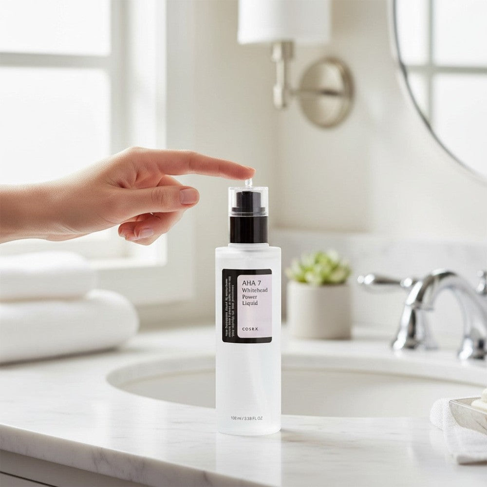 Skin TOGO Cosrx AHA 7 Whitehead Power Liquid chemical exfoliant bottle being pressed on a marble bathroom vanity