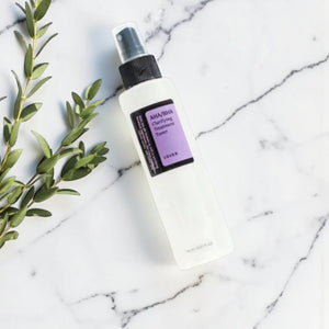 Skin TOGO COSRX AHA/BHA Clarifying Treatment Toner in a 150ml spray bottle on a white marble surface with green leaves.
