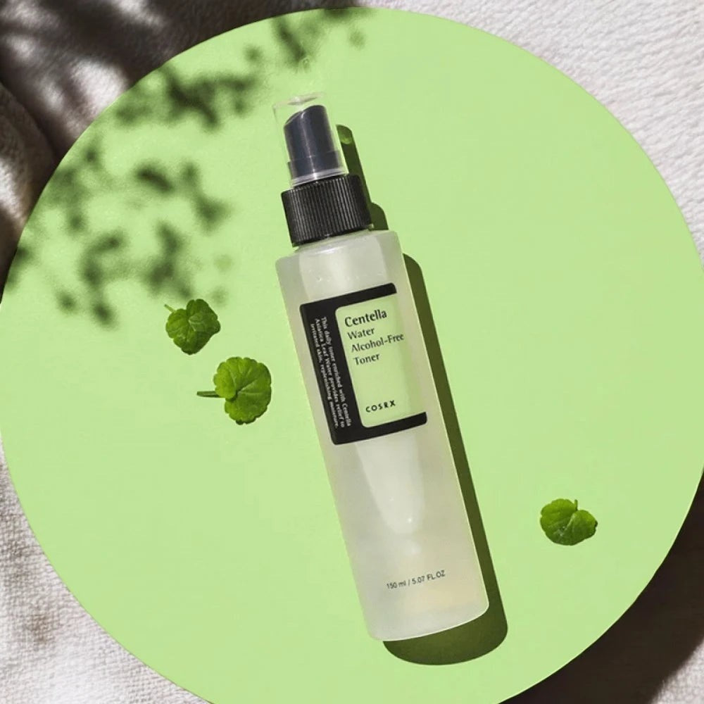 Skin TOGO Cosrx Centella Water Alcohol-Free Toner in a 150ml spray bottle on a green circular surface with leaves.