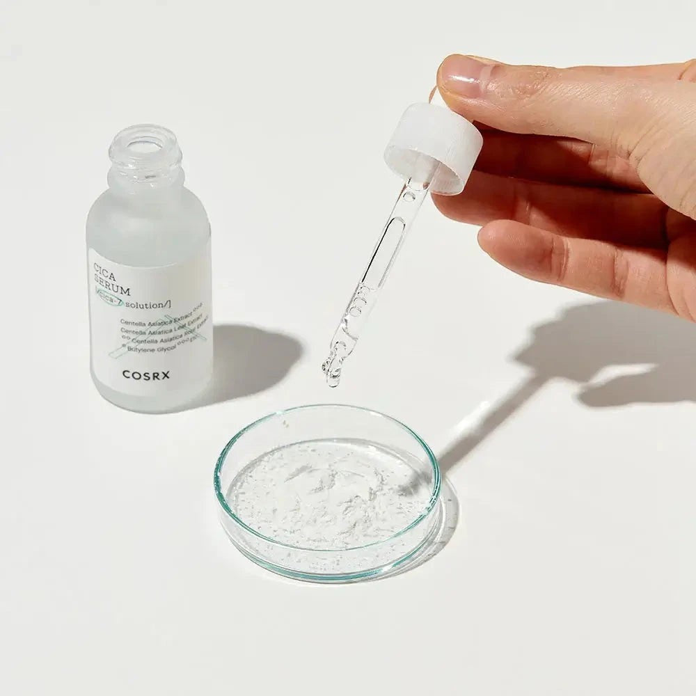 Skin TOGO COSRX Pure Fit Cica Serum bottle with a glass dropper dispensing clear liquid into a small petri dish.