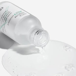 Skin TOGO COSRX Pure Fit Cica Serum bottle pouring a clear, lightweight soothing facial serum onto a white surface.