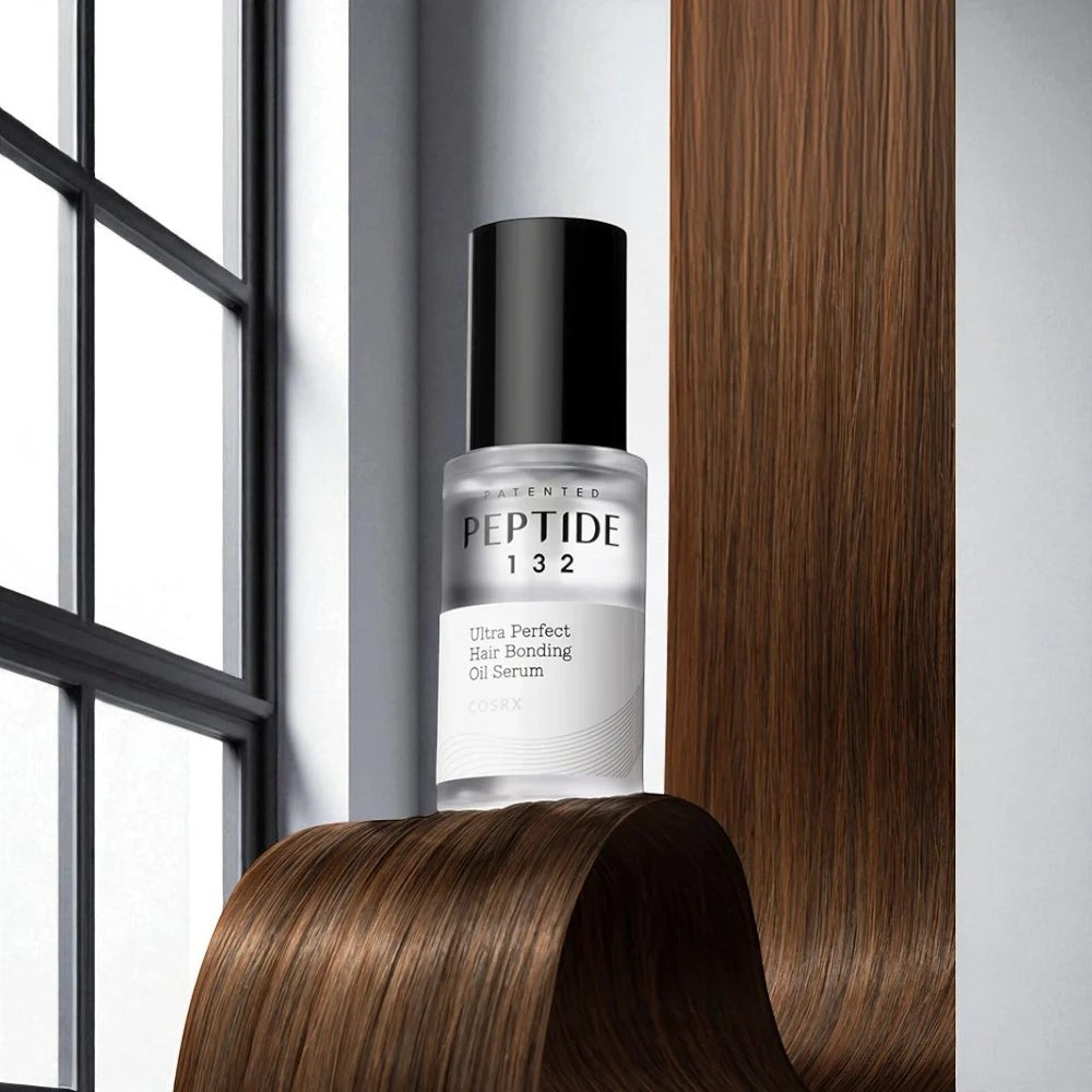 Skin TOGO COSRX Peptide-132 hair bonding oil serum bottle displayed against a backdrop of smooth brown hair.
