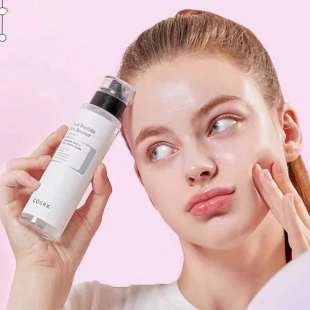 Skin TOGO model holding a bottle of COSRX 6 Peptide Skin Booster serum against a soft pink background