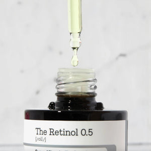Skin TOGO COSRX The Retinol 0.5 Oil serum with a dropper dispensing a drop of golden skincare oil