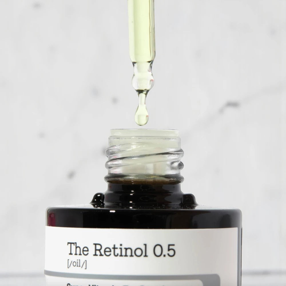 Skin TOGO COSRX The Retinol 0.5 Oil serum with a dropper dispensing a drop of golden skincare oil