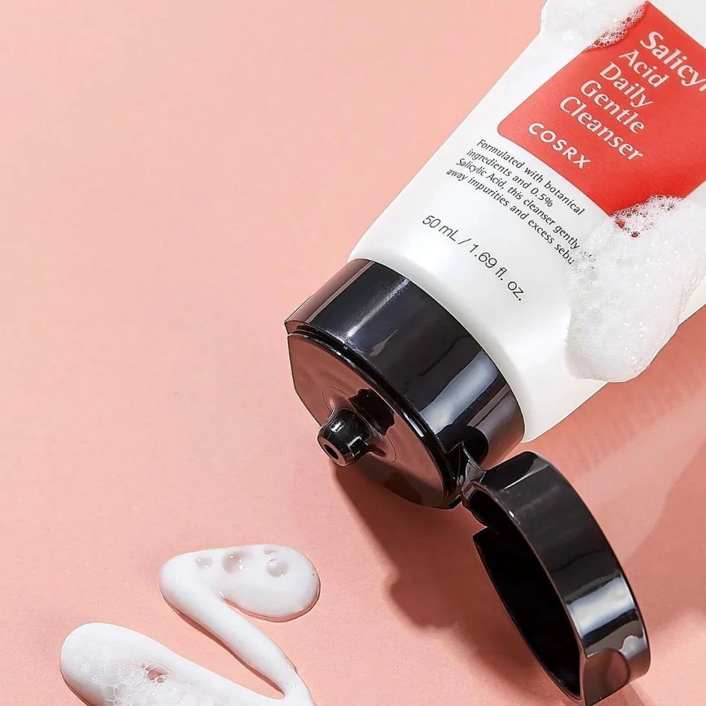 Skin TOGO Cosrx Salicylic Acid Daily Gentle Cleanser tube with creamy white foam on a soft pink background