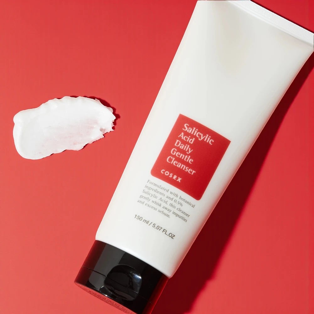 Skin TOGO Cosrx Salicylic Acid Daily Gentle Cleanser tube with a dollop of creamy face wash on a red background.