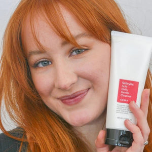 Skin TOGO model holding a white tube of Cosrx Salicylic Acid Daily Gentle Cleanser for acne-prone skin