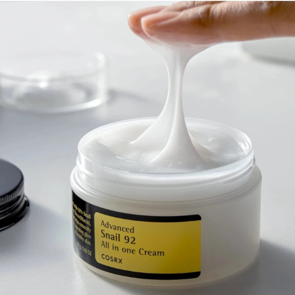 Skin TOGO Cosrx Advanced Snail 92 All In One Cream with a finger pulling a stringy, lightweight gel-cream texture.