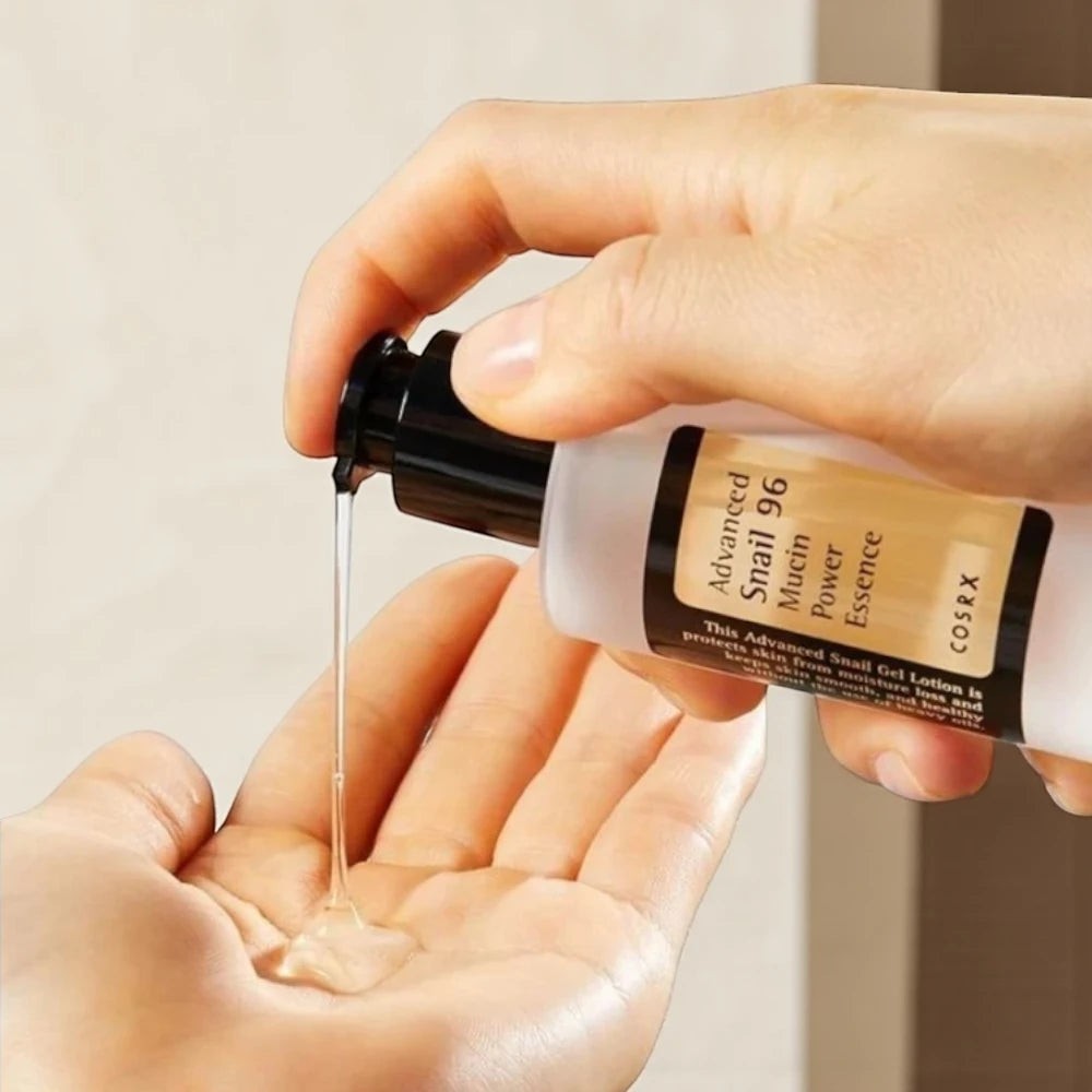 Skin TOGO Cosrx Advanced Snail 96 Mucin Power Essence being dispensed into a hand, showing its clear gel texture.