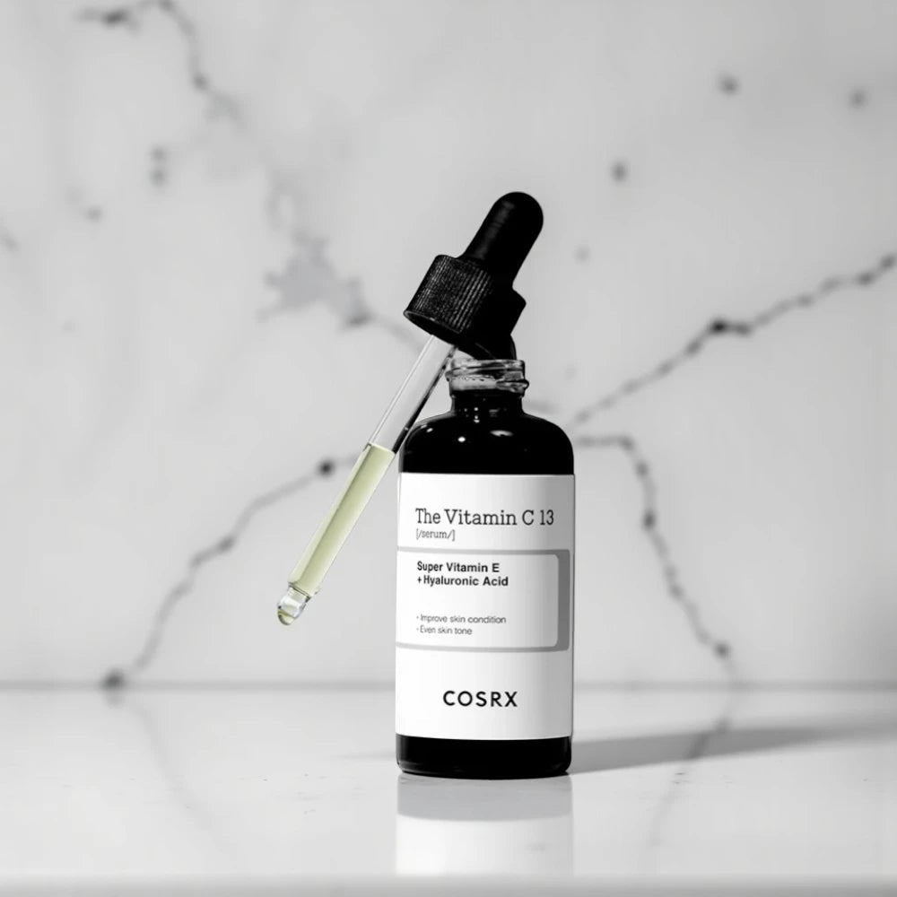 Skin TOGO COSRX The Vitamin C 13 Serum in a dark glass bottle with a dropper on a marble surface.
