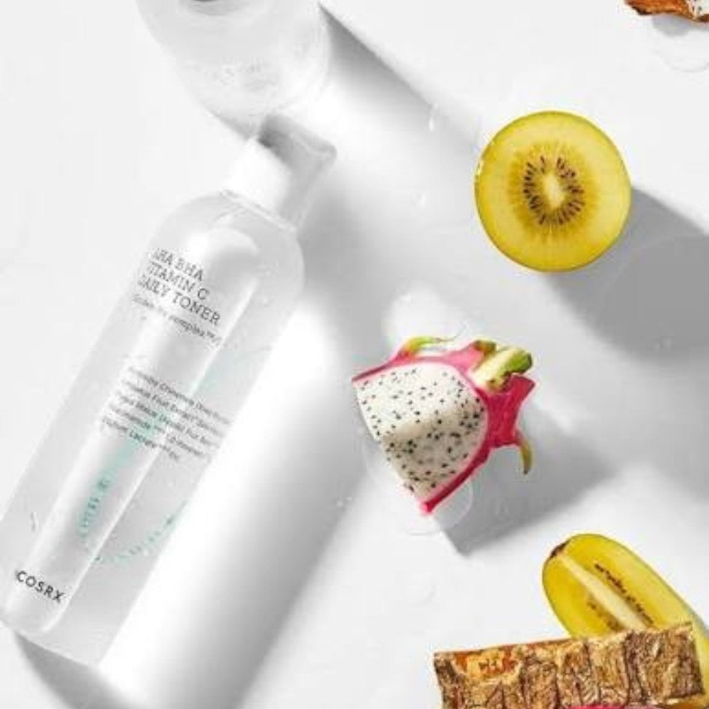 Skin TOGO COSRX AHA BHA Vitamin C Daily Toner bottle surrounded by fresh kiwi and dragon fruit slices on white.
